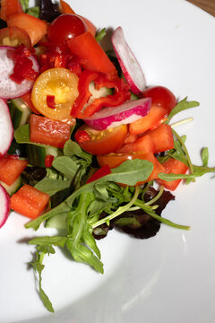 Close up of a delicious healthy side salad with leaves and radish on a white plate