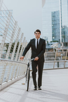 Young handsome man with business suit driving bicicyle to go to office - Corporate businessman portrait biking in the city, concepts about business, green mobility and lifestyle