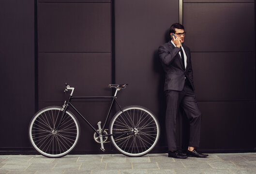 Young handsome man with business suit driving bicicyle to go to office - Corporate businessman portrait biking in the city, concepts about business, green mobility and lifestyle