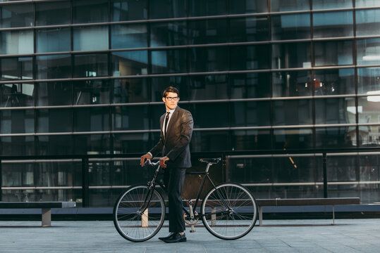 Young handsome man with business suit driving bicicyle to go to office - Corporate businessman portrait biking in the city, concepts about business, green mobility and lifestyle
