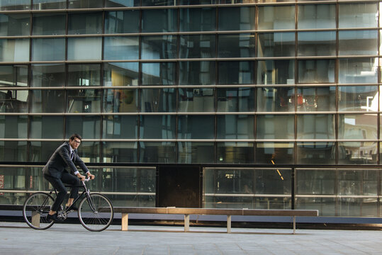 Young handsome man with business suit driving bicicyle to go to office - Corporate businessman portrait biking in the city, concepts about business, green mobility and lifestyle