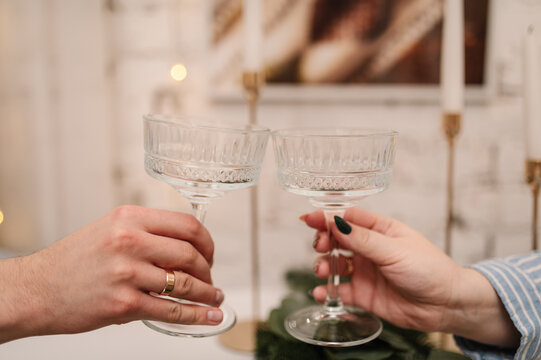Male and female hands holding glass champagne coupes, celebratory toast. Close up.