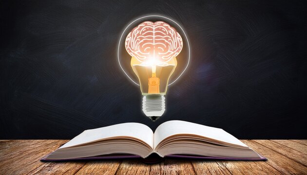 open book with glowing brain lightbulb above on wooden desk chalk board background