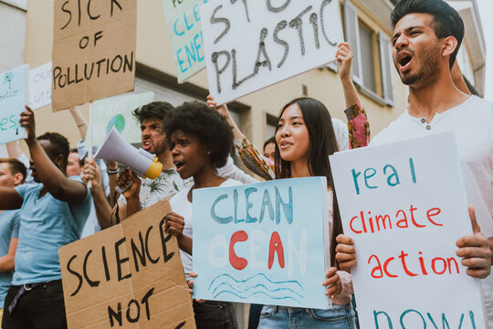 Public demonstration on the street against global warming and pollution. Group of multiethnic people making protest about climate change and plastic problems in the oceans