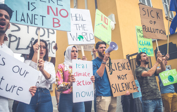 Public demonstration on the street against global warming and pollution. Group of multiethnic people making protest about climate change and plastic problems in the oceans