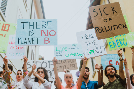 Public demonstration on the street against global warming and pollution. Group of multiethnic people making protest about climate change and plastic problems in the oceans