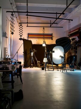 A dynamic studio scene filled with various lighting rigs and camera equipment, ready for a professional photoshoot. The warm hues create an inviting atmosphere, highlighting artistic creativity
