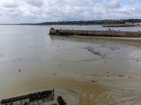 Aerial drone view of Cancale promenade and boats during low tide in Brittany, with exposed seabed and tidal landscape of the bay, France