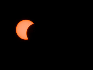 Eclipse solar parcial resplandeciente en un cielo nocturno completamente oscuro, mostrando la silueta en luna del disco solar. © Argiduna