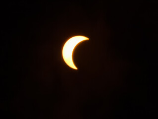 Eclipse solar parcial resplandeciente en un cielo nocturno completamente oscuro, mostrando la silueta en luna del disco solar. © Argiduna