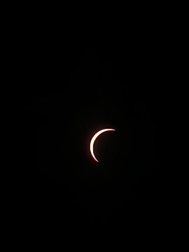 Eclipse solar parcial resplandeciente en un cielo nocturno completamente oscuro, mostrando la silueta en luna del disco solar.
