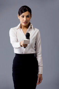 Portrait of well dressed TV reporter holding out microphone 