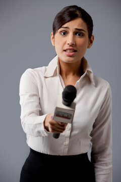 Portrait of young woman news reporter holding out microphone 