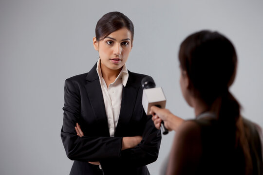 Businesswoman giving an interview to a reporter against colored background 