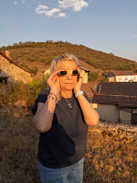 Senior woman wearing solar eclipse glasses watching sky