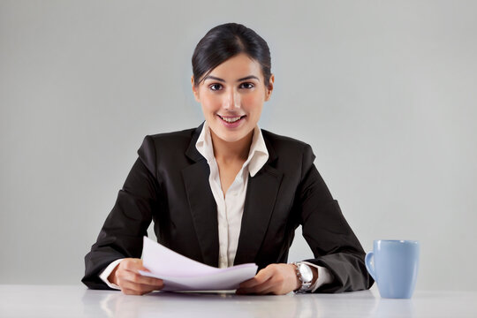 Portrait of smiling young news television host with coffee cup and paper 