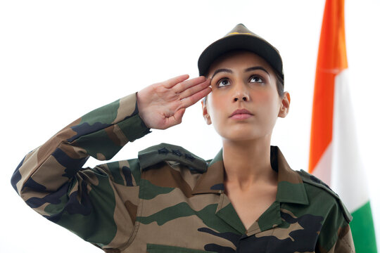 Female soldier saluting while looking up and Indian flag in background 