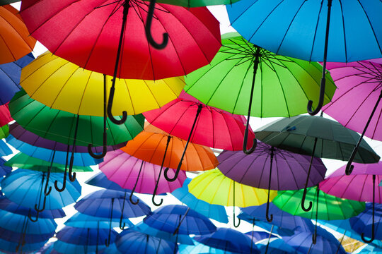 Colorful umbrellas form a repeating canopy overhead in an outdoor festival setting, vibrant decorative display, creative background.