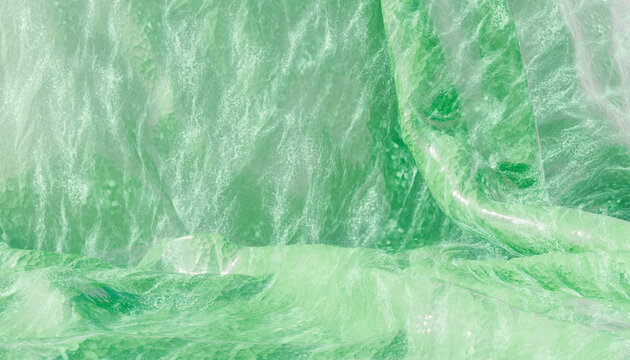 Close-up view of crumpled shiny green fabric with textured folds