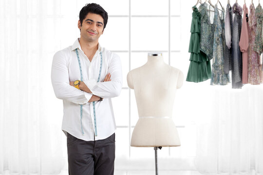 Young male fashion designer standing by mannequin in studio 