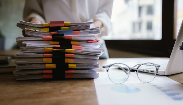 A woman in a red shirt is handling a large number of documents and files, symbolizing office work, documentation, organization, management, deadlines, workloads, bureaucracy, and business responsibili