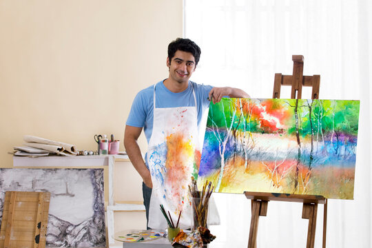 Male painter standing in front of painted canvas 