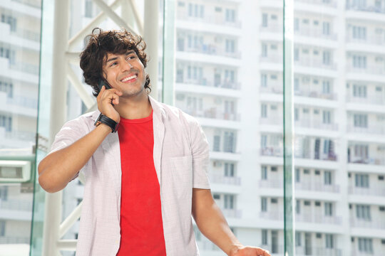 Smiling young man conversing on mobile phone 