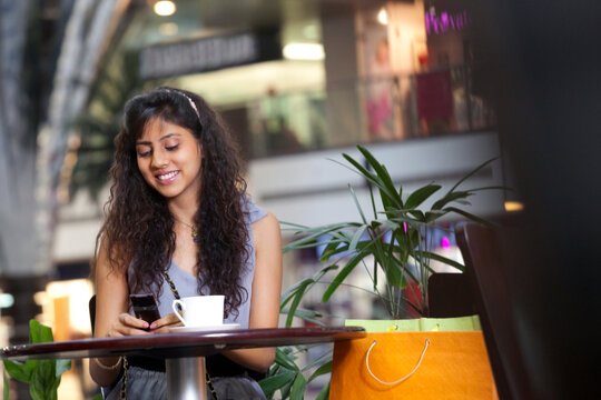 Smiling woman text messaging while sitting in cafe 