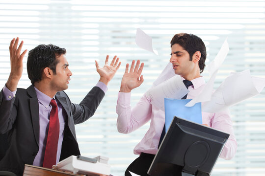 Displeased businessman throwing papers on executive 