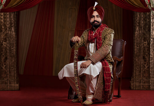 Portrait of a Sikh groom sitting with a sword 