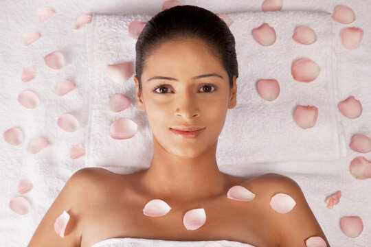 Close-up portrait of woman lying on massage table with petals 