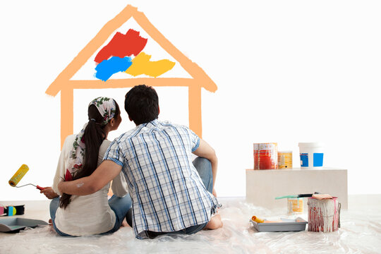 Relaxed couple watching their dream home on wall together 