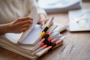 Obraz premium Business professional reviewing documents and paperwork at a desk with laptop, smartphone, calculator, and organized files in a modern office.