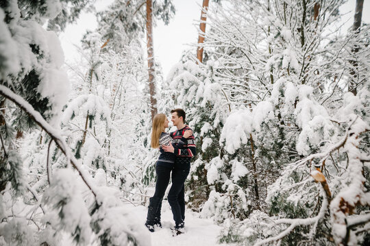 Loving couple gently hugging in a fairytale winter forest covered with snow. Happy moments of a family walk.