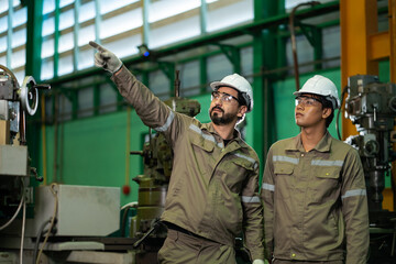 Fototapeta premium Industrial workers operating machinery in manufacturing factory