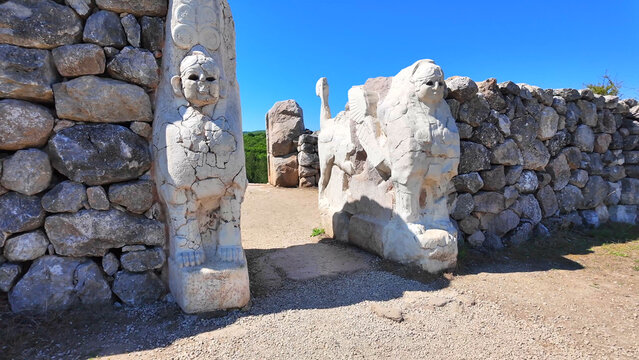 Two carved stone sphinxes guard the ancient entrance portal of the Sphinx Gate, set within stone walls at Hattusa.

