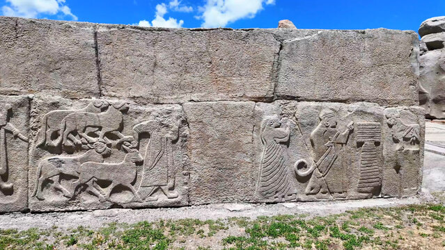 Ancient Hittite orthostat relief wall depicting a chariot wheel, lute players, and acrobats at the Alacah&ouml;y&uuml;k archaeological site, Turkey.
