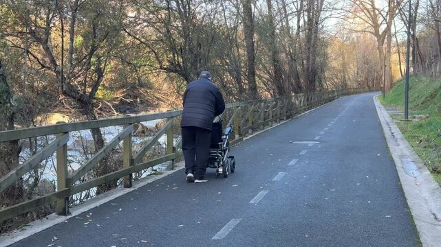 Senior man walking with baby stroller in a park