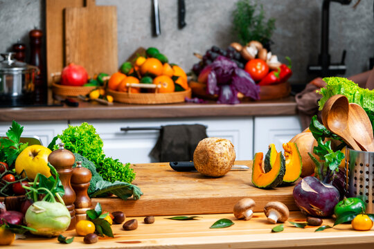 celery root and autumn vegetables on wooden board in modern kitchen. Organic healthy nutrition culinary concept.