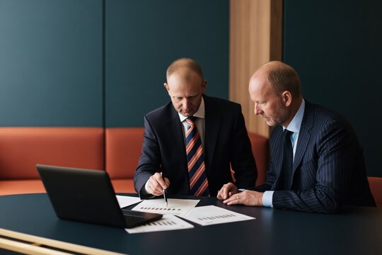 CEO and CFO reviewing financial reports and comparing investment options before making a difficult strategic business decision