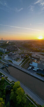 Halle, Vlaams Brabant, Belgium, 27th of April, 2025, A magnificent and beautiful sunset casting its warm glow on the urban cityscape, riverside, and modern architecture