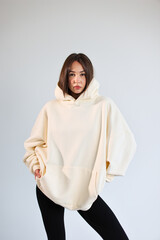 Fototapeta premium Young woman presenting empty cream hooded sweatshirt mockup, casual streetwear.