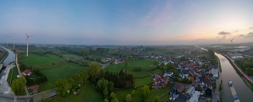 Lot, Beersel, Vlaams-Brabant, 22nd of April, 2025, Stunning aerial panorama showcasing a tranquil landscape with lush fields and winding river at sunrise.