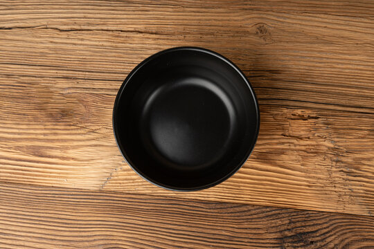 Empty bowl on table, black plate on wooden table, dark porcelain dish mockup, rustical kitchen