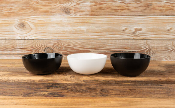 Three empty bowls on table, white porcelain, black and dishes on tabletop, rustic dish