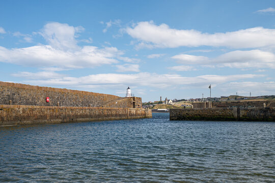 Macduff viewed from the historic stone harbour at Banff in Aberdeenshire under a bright blue sky during a calm afternoon in coastal Scotland