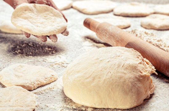Raw dough. Woman's hands rolling dough for pies. Baking at home. Homemade cakes dough in the women's hands