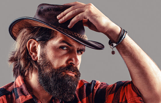 Man unshaven cowboys. Cowboy hat. Handsome young man adjusting his cowboy hat