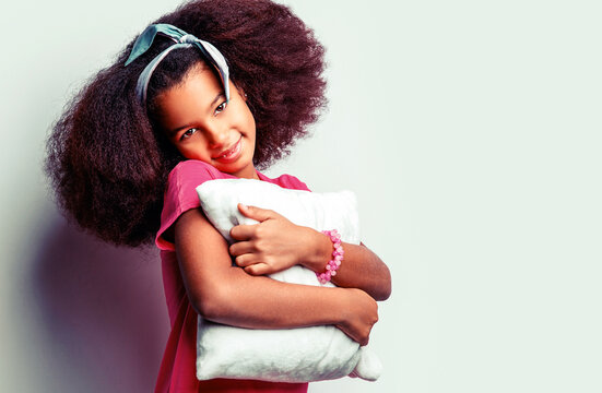 Pillow. Children girl holding a pillow on a white background. Smiling kid girl holding cushion. Girl hold pillow