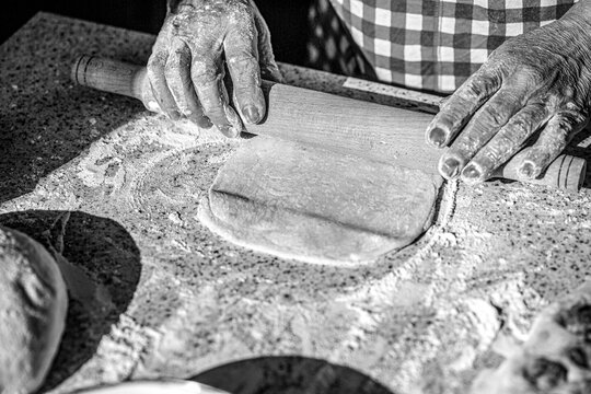 Baking background, top view. Man rolling out dough on kitchen table, close up. Black and white